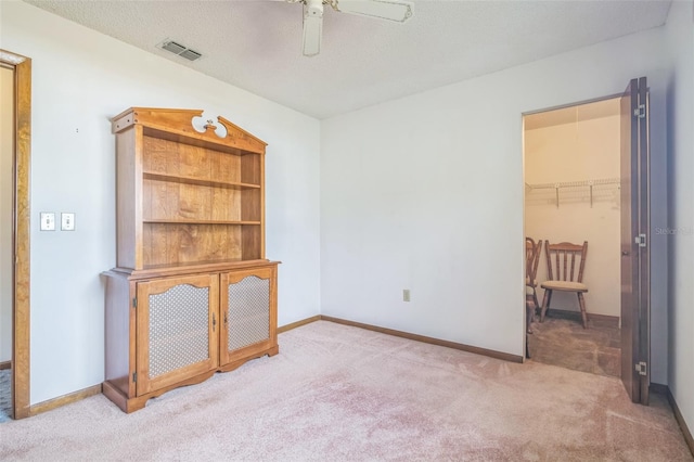 spare room featuring light carpet, a textured ceiling, and ceiling fan