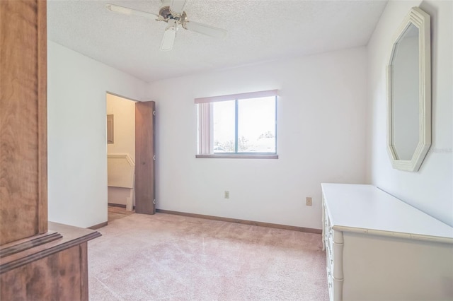 unfurnished bedroom featuring ceiling fan, a textured ceiling, light carpet, and a closet