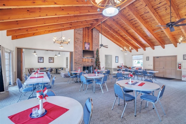 carpeted dining room featuring wooden ceiling, a brick fireplace, beamed ceiling, high vaulted ceiling, and ceiling fan with notable chandelier