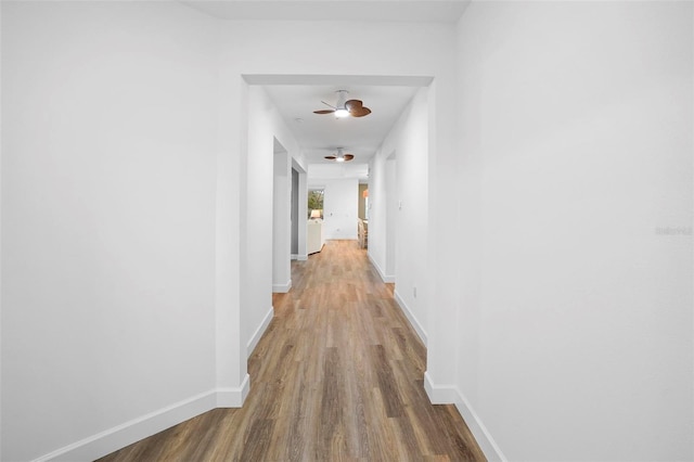 corridor with baseboards and wood finished floors