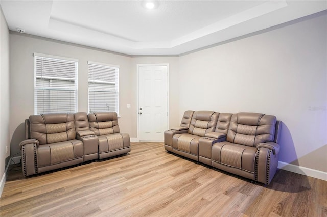 living room featuring baseboards, a raised ceiling, and light wood-style floors