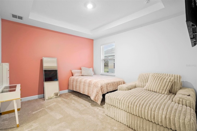 bedroom featuring baseboards, visible vents, a raised ceiling, and light colored carpet