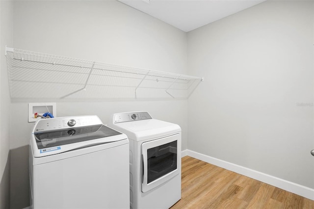 laundry room featuring laundry area, independent washer and dryer, baseboards, and wood finished floors