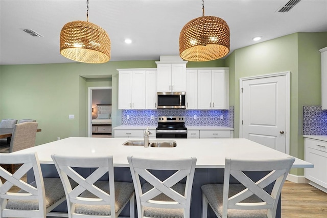 kitchen featuring stainless steel appliances, light countertops, visible vents, and pendant lighting