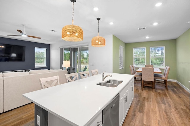 kitchen with open floor plan, light countertops, a center island with sink, and decorative light fixtures