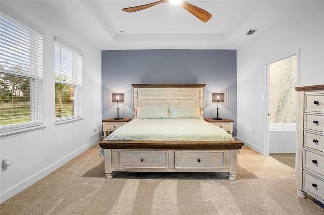 bedroom with light colored carpet, a raised ceiling, visible vents, and baseboards