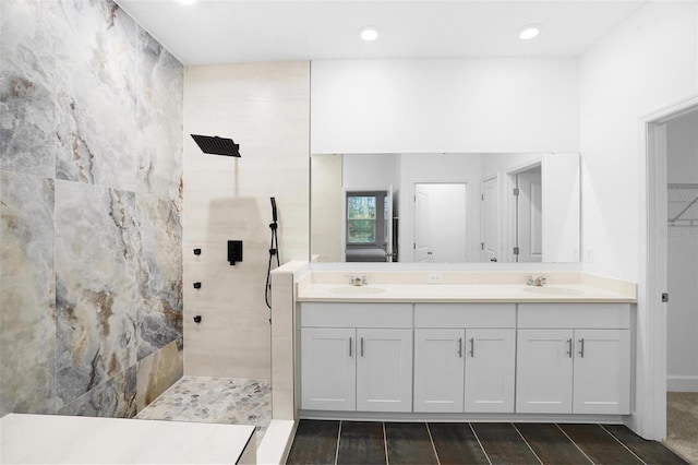 full bathroom featuring double vanity, a walk in shower, and a sink