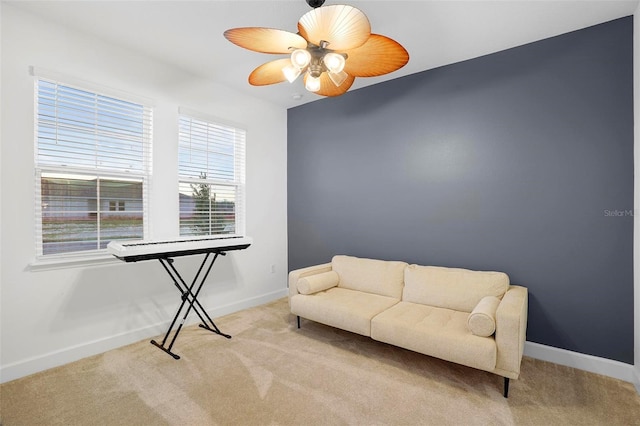 sitting room with a ceiling fan, light carpet, and baseboards