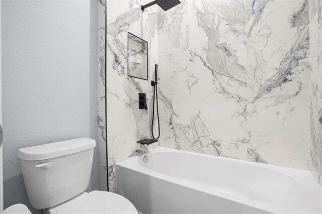 bathroom featuring toilet, a textured wall, and shower / bathtub combination