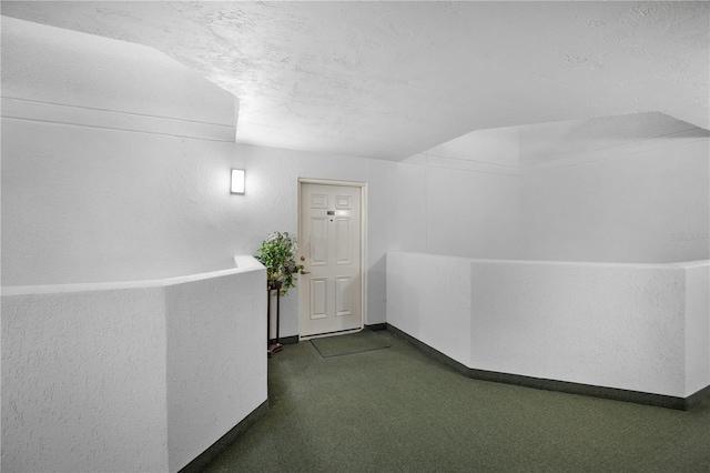 hall featuring dark colored carpet and a textured ceiling