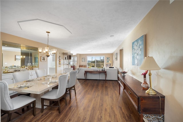 dining room with dark hardwood / wood-style floors, a textured ceiling, sink, and an inviting chandelier