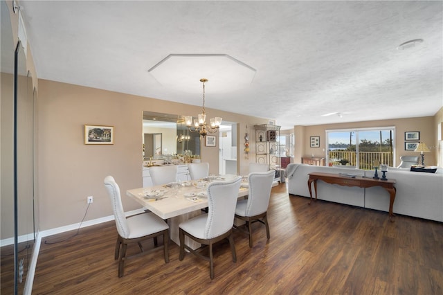 dining space with a textured ceiling, dark wood-type flooring, and a chandelier