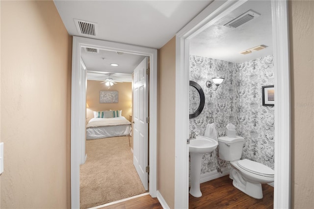 bathroom with toilet, hardwood / wood-style floors, and ceiling fan