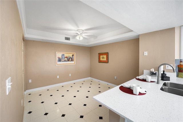 kitchen with a tray ceiling, sink, and ceiling fan