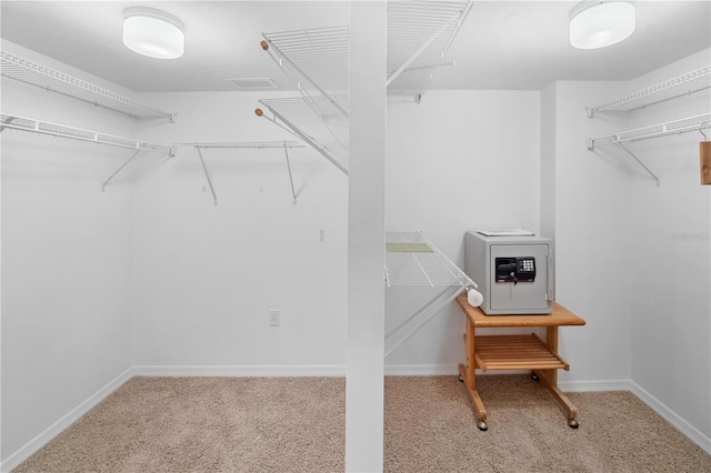 walk in closet with light carpet