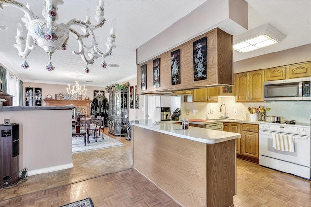 kitchen with kitchen peninsula, light parquet flooring, a chandelier, ornamental molding, and white appliances