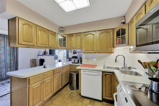 kitchen with kitchen peninsula, white appliances, backsplash, sink, and light parquet flooring