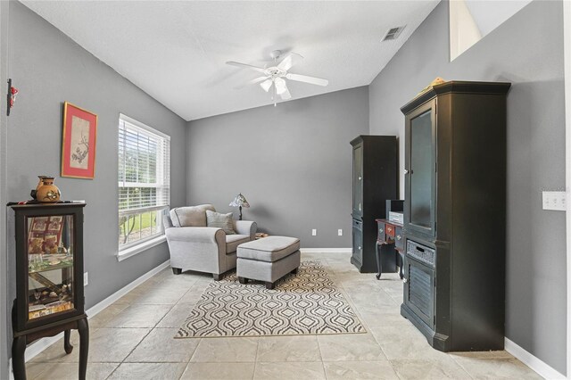 living area with ceiling fan, light tile patterned floors, and lofted ceiling