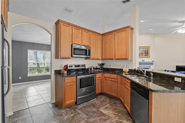 kitchen featuring ceiling fan, sink, stainless steel appliances, and dark stone counters