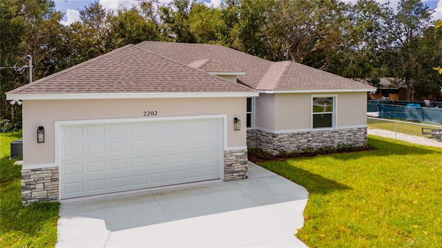 view of front of property with a garage, central AC, and a front yard