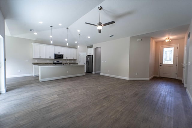 kitchen featuring dark hardwood / wood-style flooring, a center island with sink, vaulted ceiling, white cabinetry, and appliances with stainless steel finishes