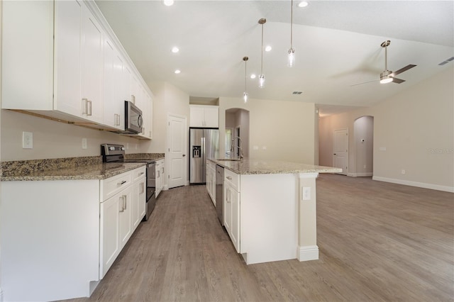 kitchen featuring stainless steel appliances, white cabinetry, hanging light fixtures, a kitchen island with sink, and light wood-type flooring