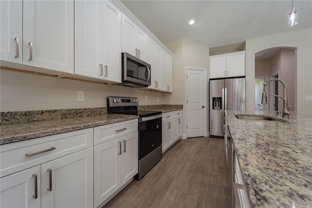 kitchen with stainless steel appliances, light stone countertops, sink, light hardwood / wood-style floors, and white cabinets