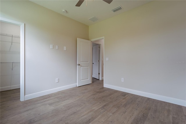 unfurnished bedroom with a closet, light wood-type flooring, a walk in closet, and ceiling fan