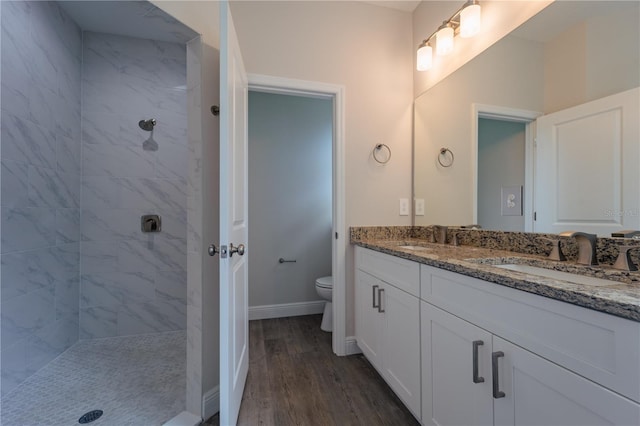 bathroom featuring tiled shower, hardwood / wood-style floors, vanity, and toilet