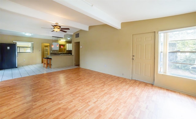 unfurnished living room with vaulted ceiling with beams, light hardwood / wood-style floors, and ceiling fan