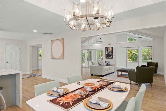 dining room featuring lofted ceiling, french doors, light hardwood / wood-style flooring, and a chandelier