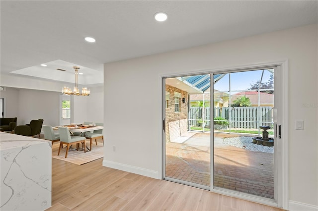 doorway to outside featuring a chandelier and light wood-type flooring