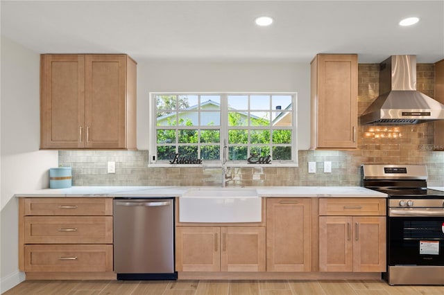 kitchen featuring tasteful backsplash, appliances with stainless steel finishes, light wood-type flooring, wall chimney exhaust hood, and sink