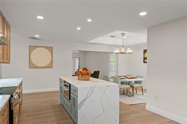 kitchen with a kitchen island, stainless steel appliances, pendant lighting, light stone counters, and light hardwood / wood-style floors