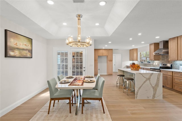 dining room featuring light hardwood / wood-style floors, a raised ceiling, and an inviting chandelier