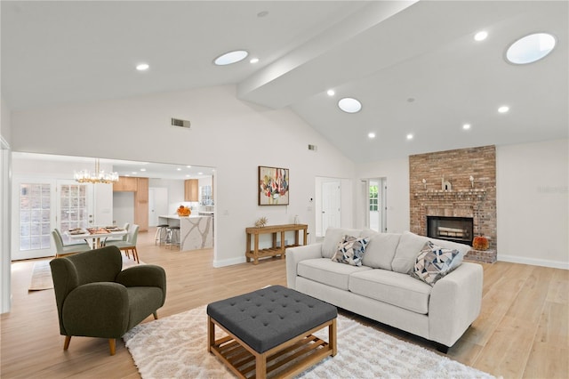 living room featuring light hardwood / wood-style floors, a notable chandelier, high vaulted ceiling, and a large fireplace