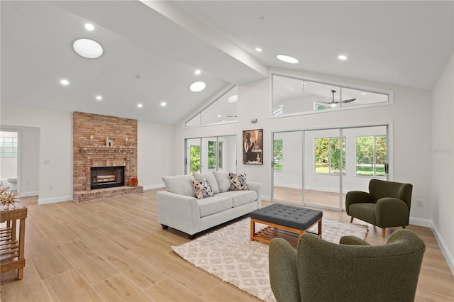 living room featuring ceiling fan, high vaulted ceiling, light wood-type flooring, and a brick fireplace