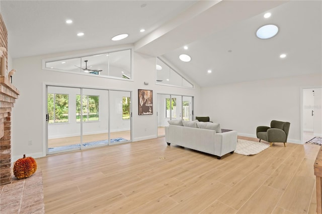 living room with light hardwood / wood-style floors, ceiling fan, high vaulted ceiling, and a brick fireplace