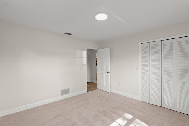 unfurnished bedroom with a closet and light colored carpet