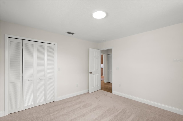 unfurnished bedroom with a closet and light colored carpet