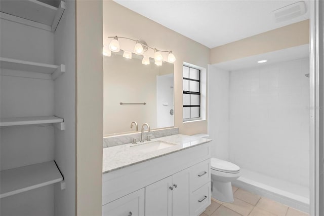 bathroom with tile patterned flooring, vanity, toilet, and a tile shower