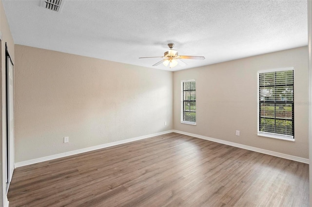 unfurnished room with a wealth of natural light, ceiling fan, a textured ceiling, and hardwood / wood-style flooring