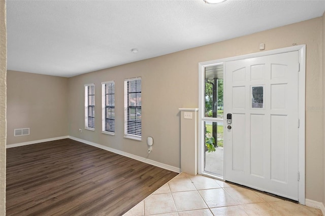 foyer with a textured ceiling and light hardwood / wood-style flooring