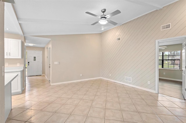 tiled empty room featuring ceiling fan and lofted ceiling with beams