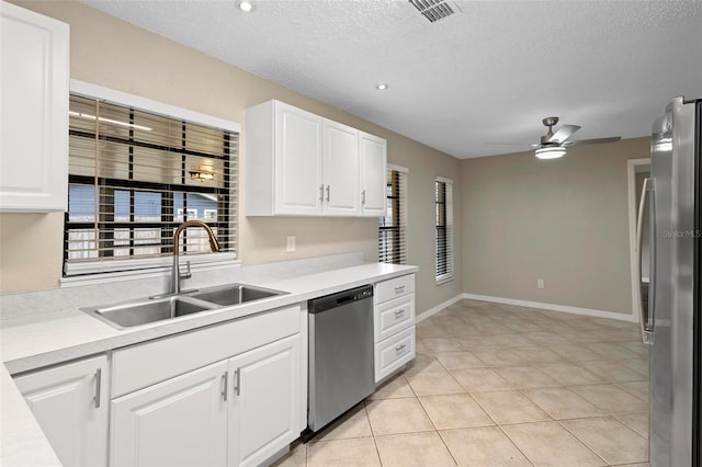 kitchen featuring stainless steel appliances, sink, light tile patterned floors, ceiling fan, and white cabinetry