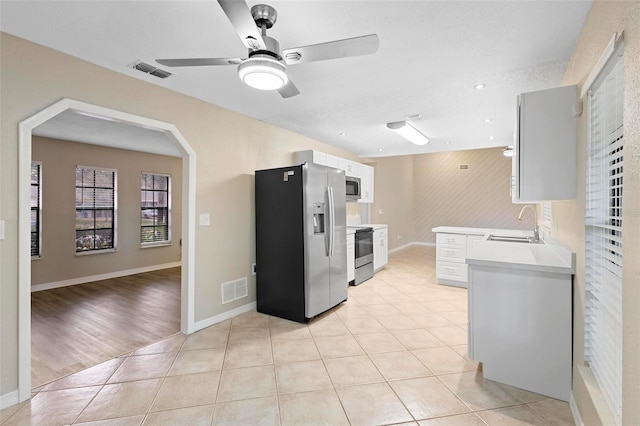 kitchen with light hardwood / wood-style floors, sink, appliances with stainless steel finishes, a textured ceiling, and white cabinets