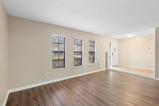 spare room with light hardwood / wood-style floors and a textured ceiling