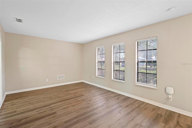 empty room with wood-type flooring and a textured ceiling