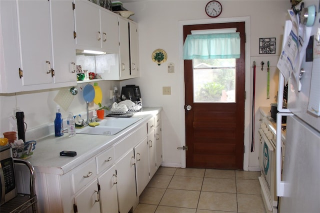 kitchen featuring light tile patterned flooring, white cabinets, sink, and white appliances