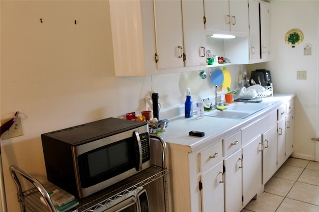 kitchen with sink, white cabinets, and light tile patterned flooring